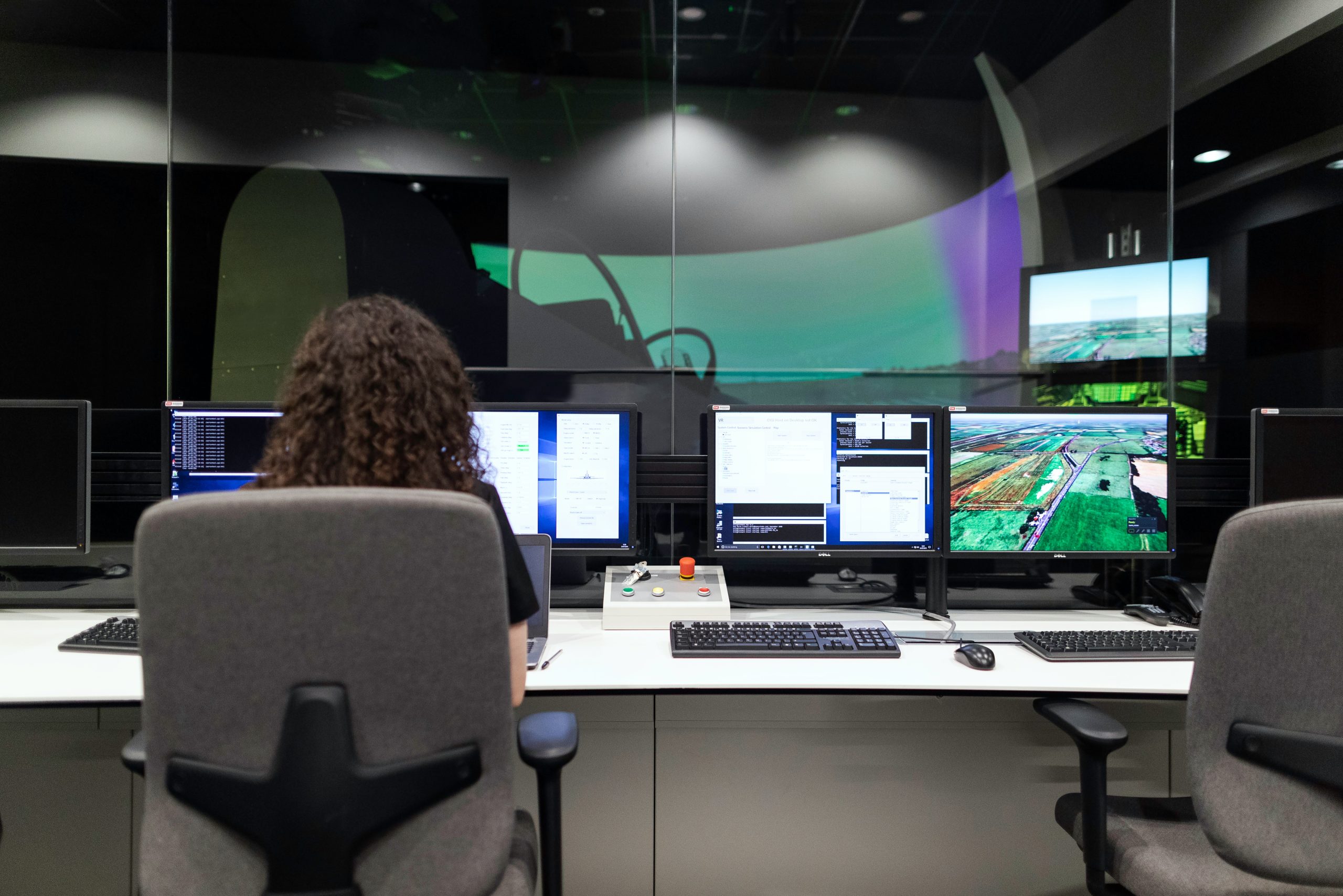 IT professional overseeing multiple system interfaces and performance data on several monitors.