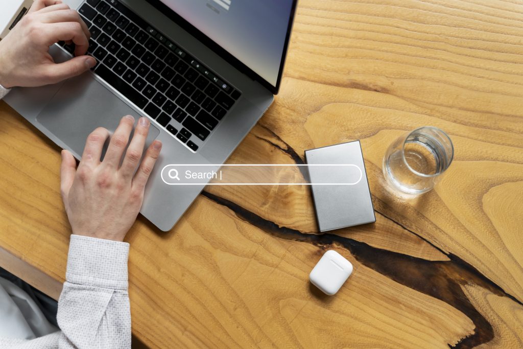Hands typing on a laptop at a wooden desk.