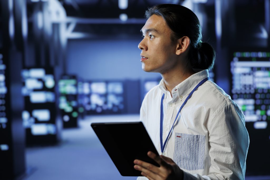 Young technician holding tablet in a modern server room.