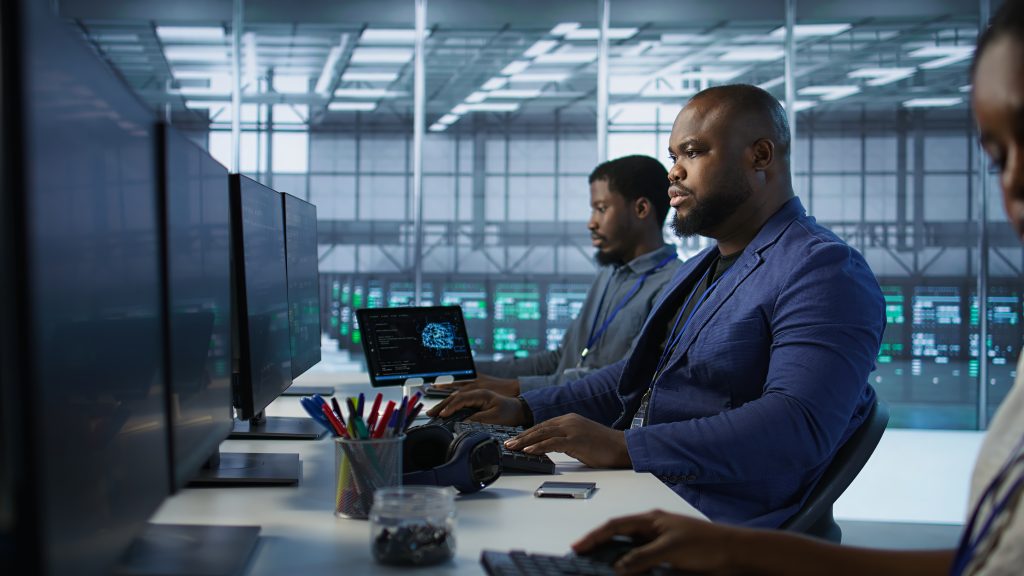 IT specialists working at monitors in a modern operations center.